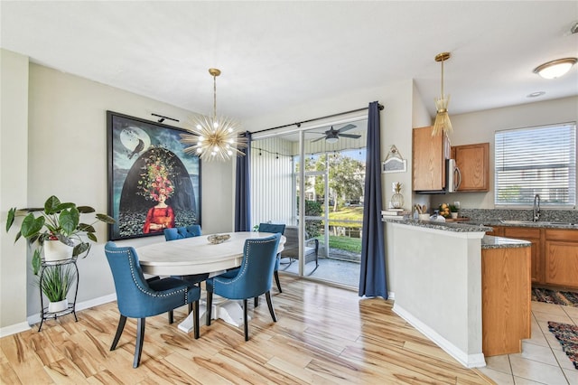 dining space with sink, light wood-type flooring, and an inviting chandelier