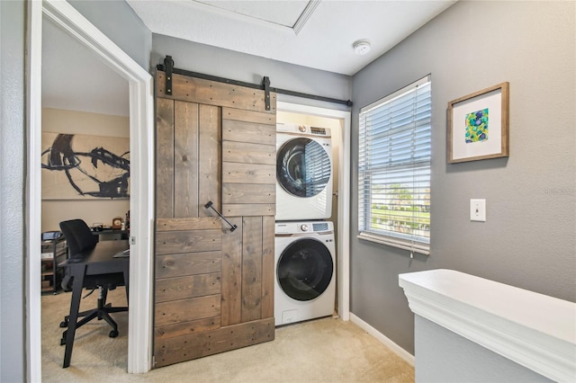 washroom featuring a barn door, stacked washer / dryer, and light carpet