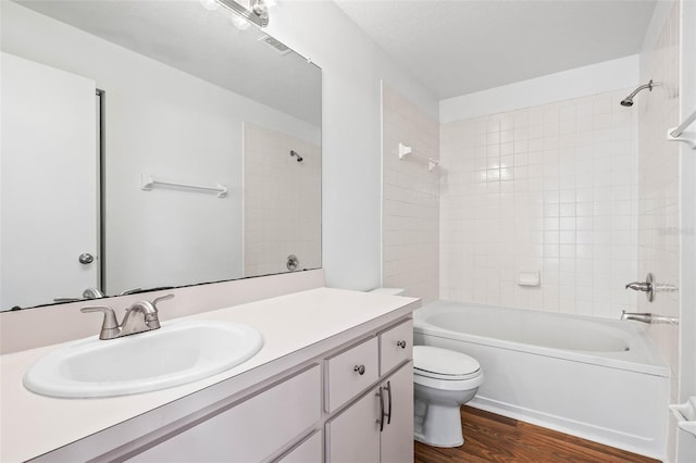 full bathroom with hardwood / wood-style flooring, vanity, toilet, and tiled shower / bath combo