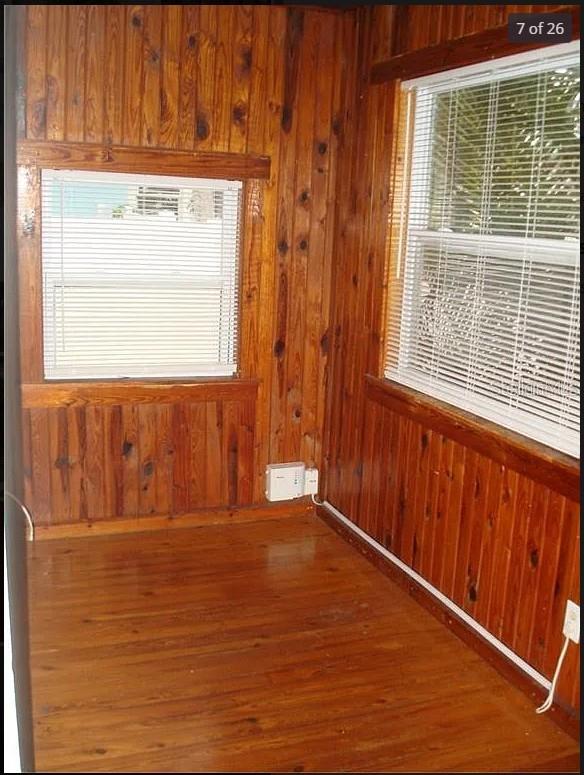 unfurnished room featuring wood walls, wood-type flooring, and a wealth of natural light