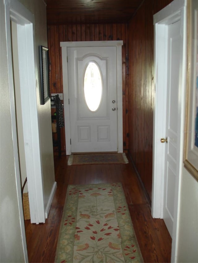 doorway with wood walls and dark wood-type flooring