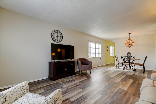 living room featuring hardwood / wood-style floors, a textured ceiling, and an inviting chandelier