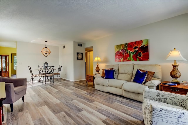 living room featuring light wood-type flooring and an inviting chandelier