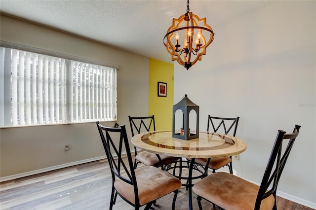 dining room with a chandelier, a textured ceiling, and light hardwood / wood-style floors