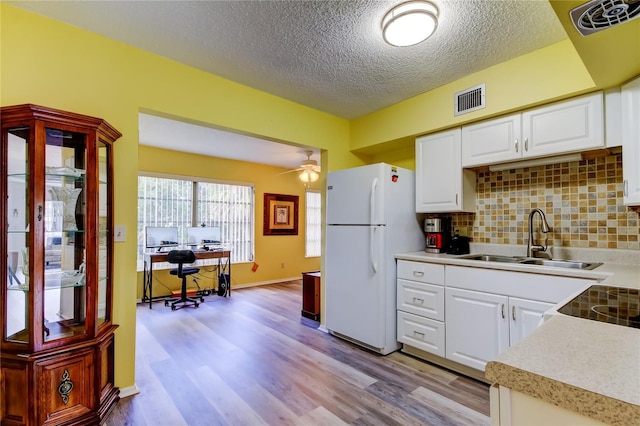 kitchen featuring a textured ceiling, ceiling fan, sink, white refrigerator, and white cabinetry