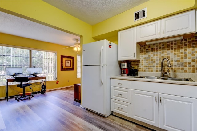 kitchen with white cabinets, sink, ceiling fan, decorative backsplash, and white fridge