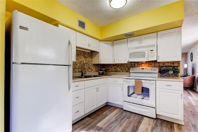 kitchen with white cabinets, decorative backsplash, white appliances, and sink