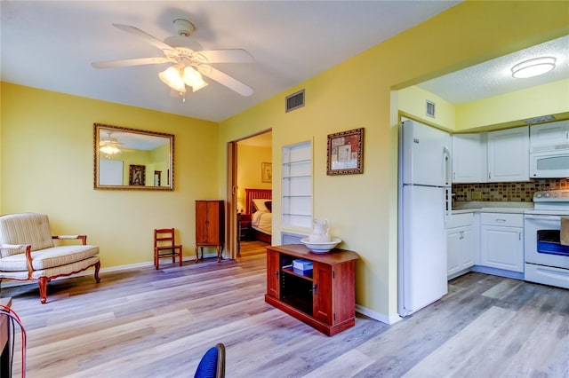 kitchen featuring white cabinetry, ceiling fan, light hardwood / wood-style floors, white appliances, and decorative backsplash