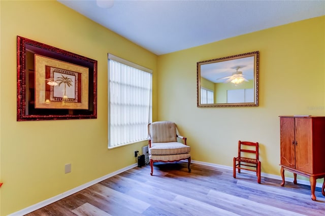 living area with light hardwood / wood-style floors and ceiling fan