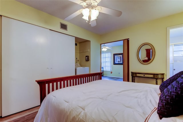 bedroom with washing machine and dryer, ensuite bathroom, ceiling fan, and light hardwood / wood-style floors