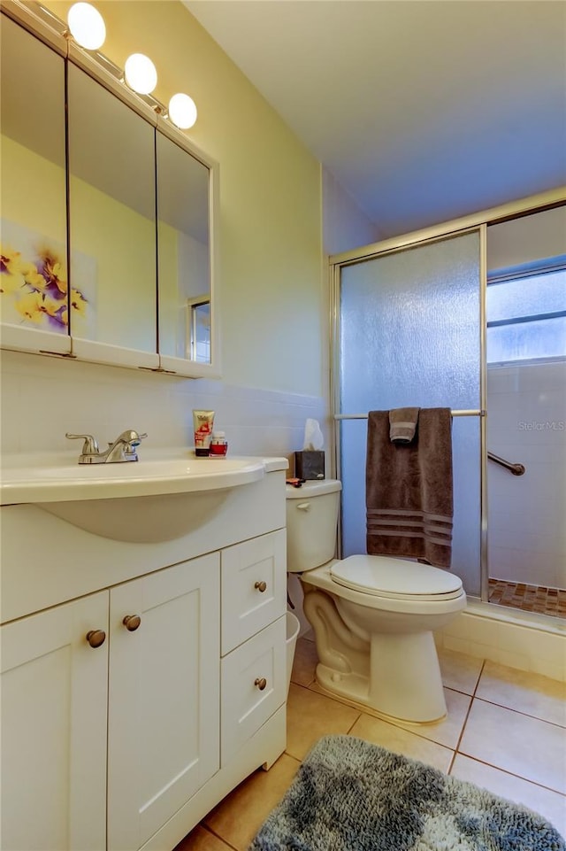 bathroom featuring tile patterned flooring, vanity, toilet, and a shower with door