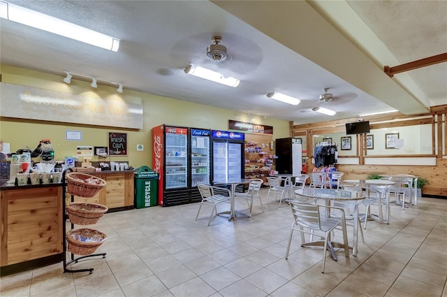 interior space featuring ceiling fan, wood walls, and a textured ceiling