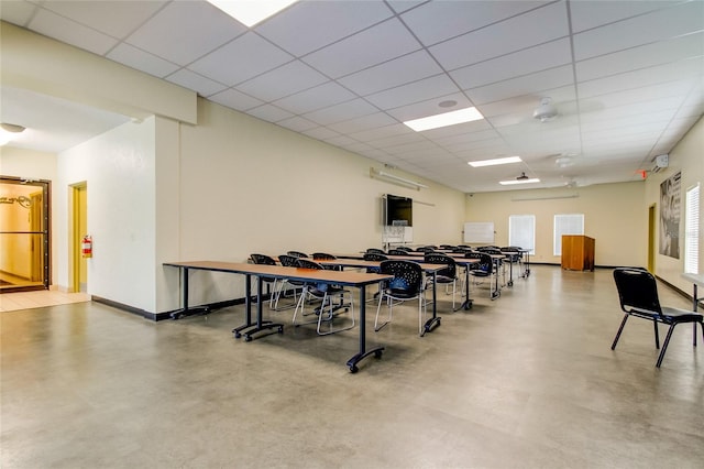 dining space featuring a drop ceiling and concrete floors