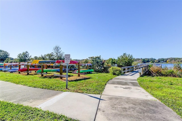 view of property's community featuring a playground, a water view, and a lawn