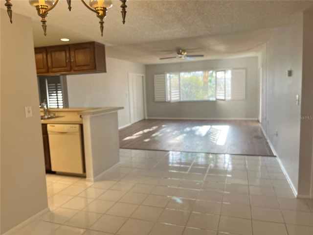 kitchen featuring light tile patterned floors, ceiling fan with notable chandelier, white dishwasher, and a textured ceiling