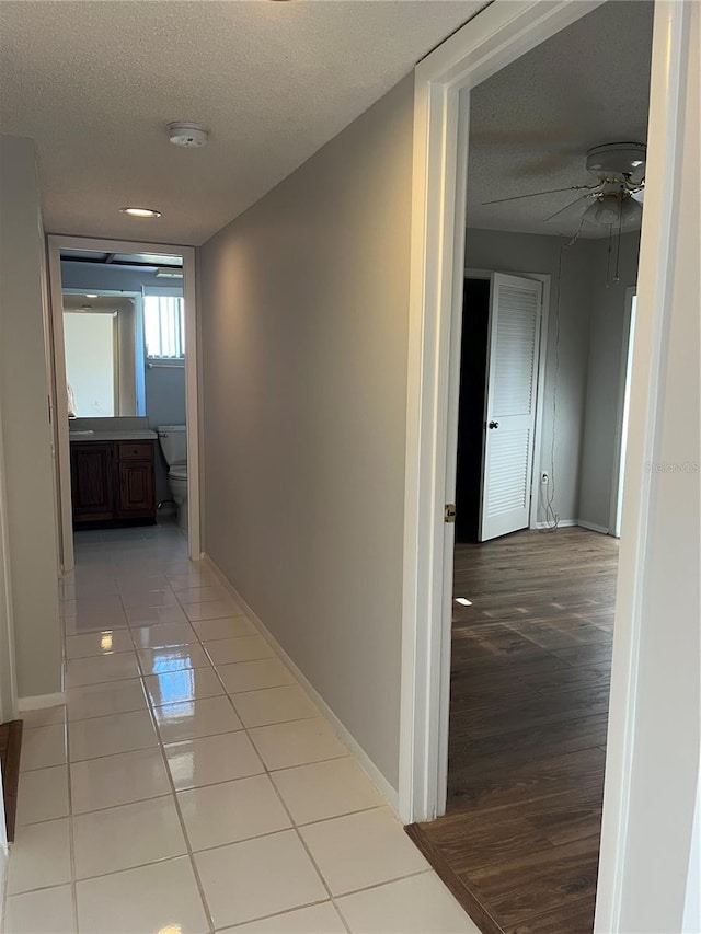 hallway with a textured ceiling and light tile patterned flooring