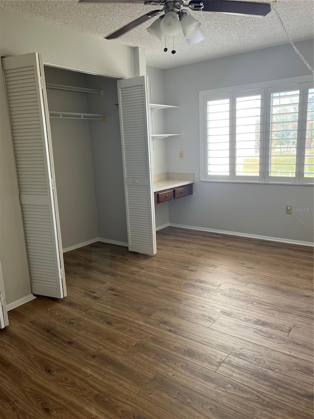 unfurnished bedroom featuring a textured ceiling, dark hardwood / wood-style flooring, and ceiling fan