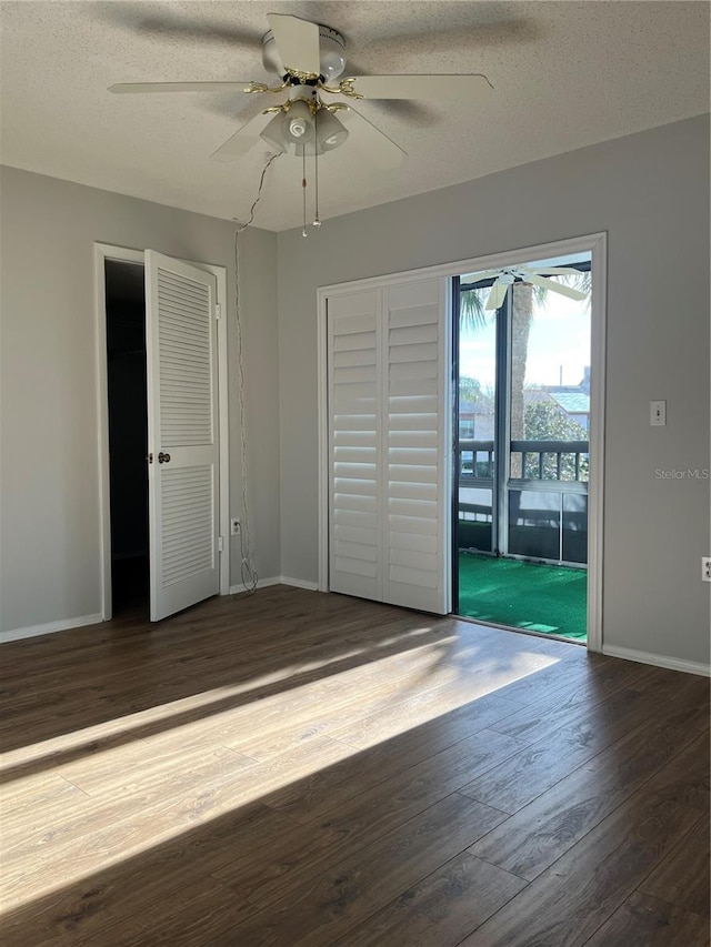 unfurnished bedroom with ceiling fan, dark hardwood / wood-style flooring, a textured ceiling, and access to outside