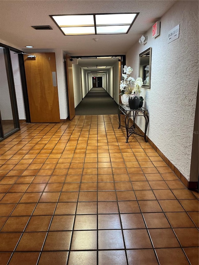 hallway featuring tile patterned flooring and a textured ceiling