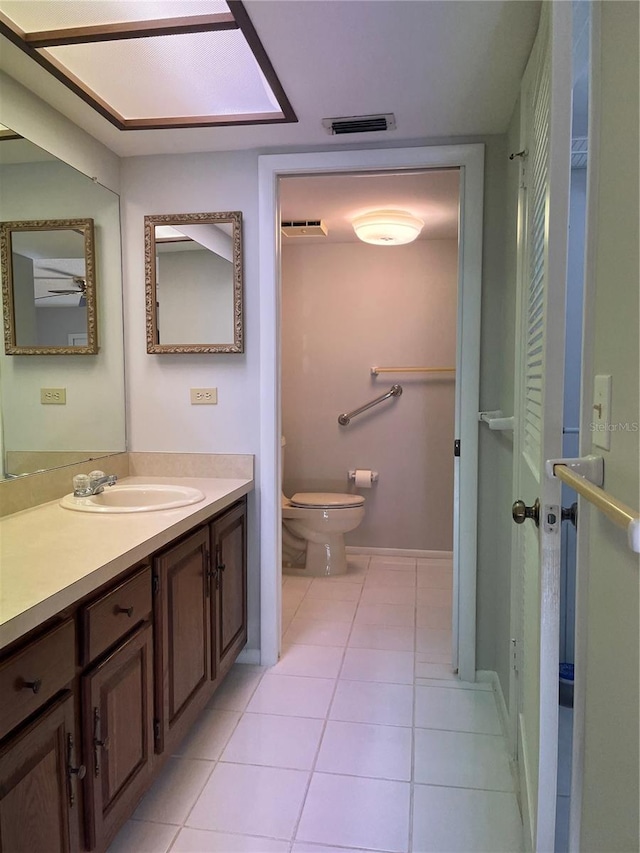 bathroom featuring tile patterned floors, vanity, toilet, and a skylight