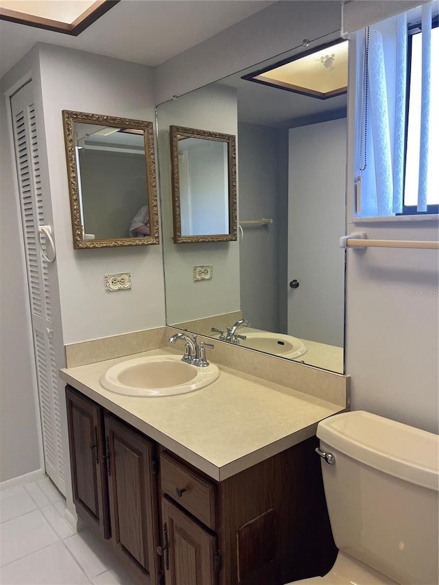 bathroom with toilet, vanity, and tile patterned floors