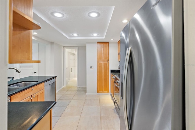 kitchen with sink, light tile patterned floors, a textured ceiling, and appliances with stainless steel finishes