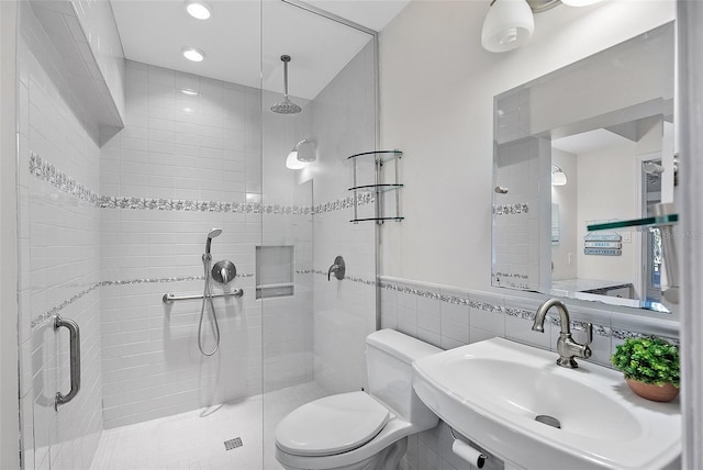 bathroom with toilet, tile walls, a shower with shower door, and sink