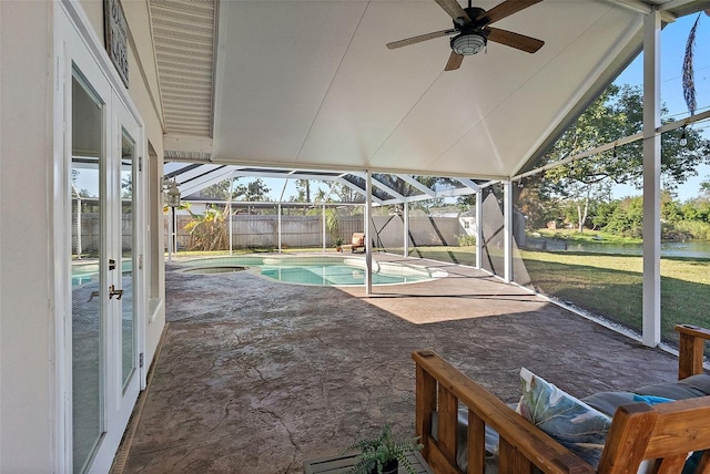 exterior space featuring a lawn, glass enclosure, ceiling fan, french doors, and a patio area