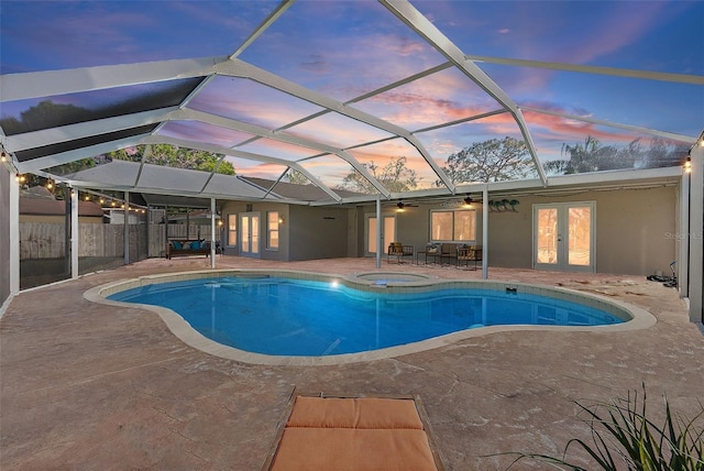 pool at dusk with glass enclosure, a patio, and french doors