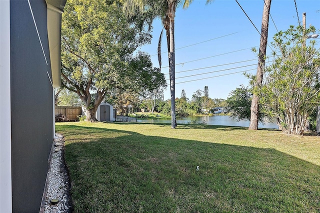 view of yard featuring a water view and a storage shed