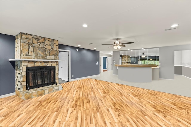 unfurnished living room with a fireplace, wood-type flooring, and ceiling fan