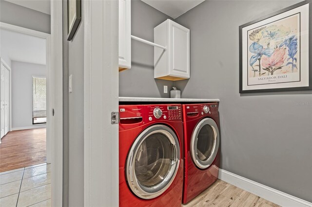 laundry room featuring washer and clothes dryer, cabinets, and light hardwood / wood-style flooring