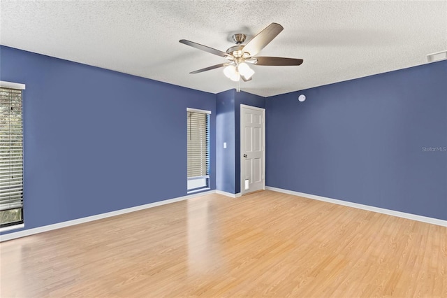 empty room with ceiling fan, a textured ceiling, and light wood-type flooring