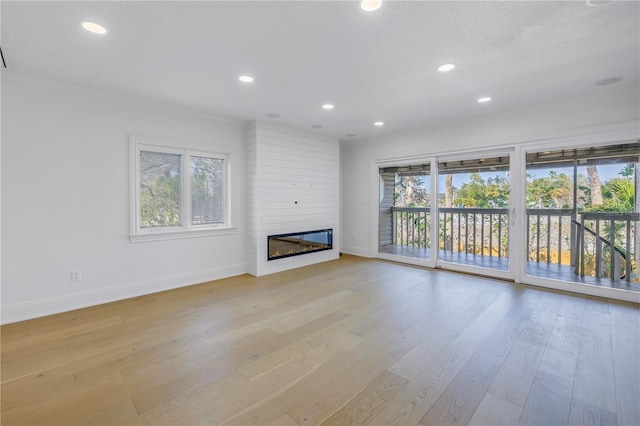 unfurnished living room with a large fireplace and light hardwood / wood-style flooring