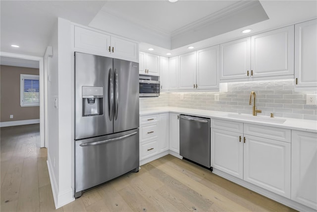 kitchen with appliances with stainless steel finishes, sink, white cabinets, and backsplash