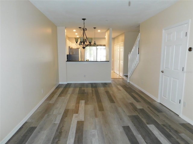 empty room with stairs, recessed lighting, baseboards, and wood finished floors