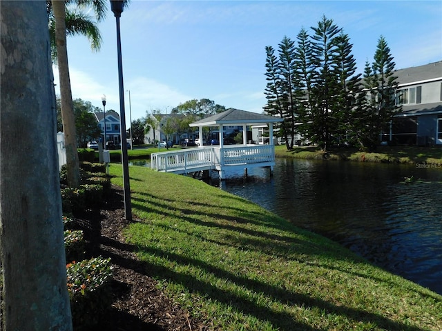 dock area with a gazebo, a lawn, and a water view