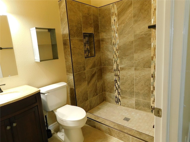 bathroom with tiled shower, vanity, and toilet