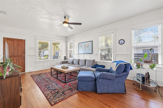 living room featuring ceiling fan, wood-type flooring, and a textured ceiling