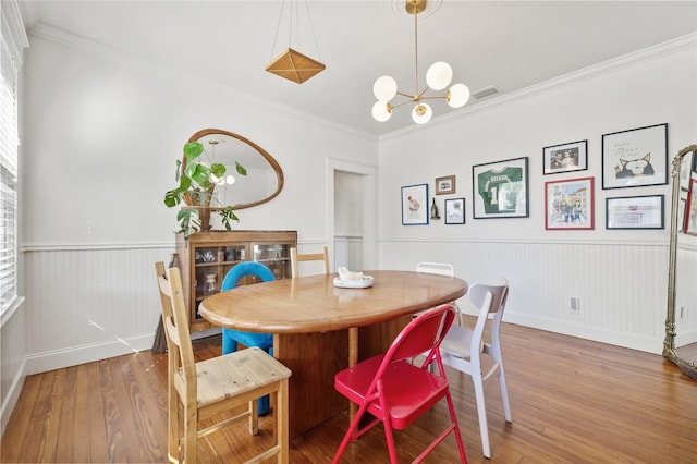 dining area featuring hardwood / wood-style floors, an inviting chandelier, and crown molding