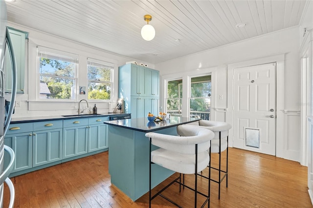 kitchen featuring sink, hanging light fixtures, blue cabinets, wood ceiling, and light wood-type flooring