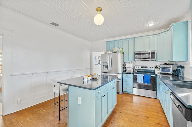 kitchen with pendant lighting, light hardwood / wood-style floors, appliances with stainless steel finishes, a kitchen island, and wood ceiling