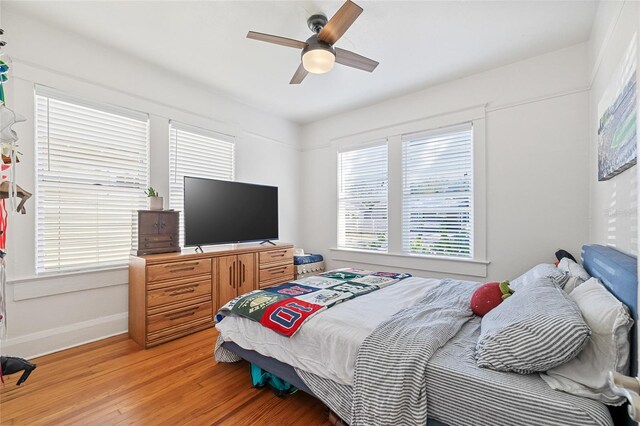 bedroom with multiple windows, ceiling fan, and hardwood / wood-style flooring