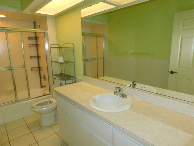 full bathroom featuring tile patterned floors, vanity, toilet, and bath / shower combo with glass door