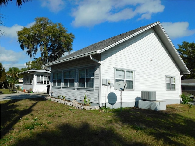 rear view of house featuring a sunroom, central AC unit, and a yard