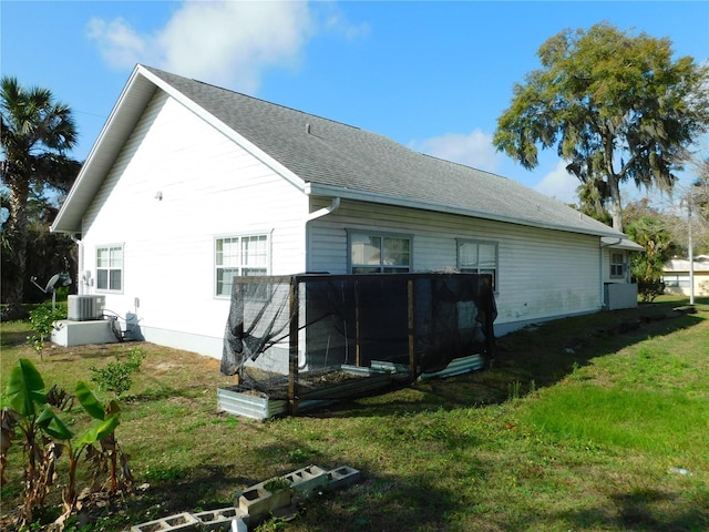 view of side of property with central AC unit and a yard