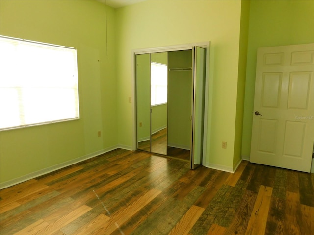 unfurnished bedroom featuring a closet and dark hardwood / wood-style flooring