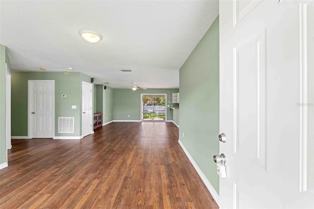 unfurnished living room with visible vents, dark wood finished floors, baseboards, and ceiling fan