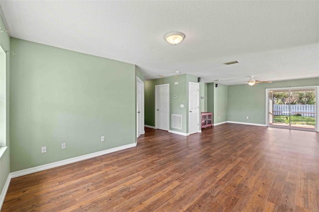 spare room featuring baseboards, a textured ceiling, visible vents, and dark wood-type flooring