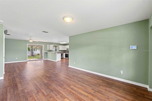 unfurnished living room with baseboards, visible vents, ceiling fan, dark wood-style flooring, and a textured ceiling